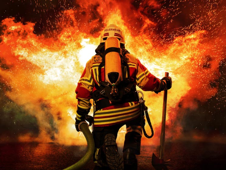 A firefighter kneels before the fire.